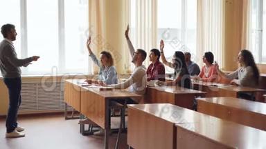 年轻的学生举手回答老师`问题，而留胡子的教授则在讲话
